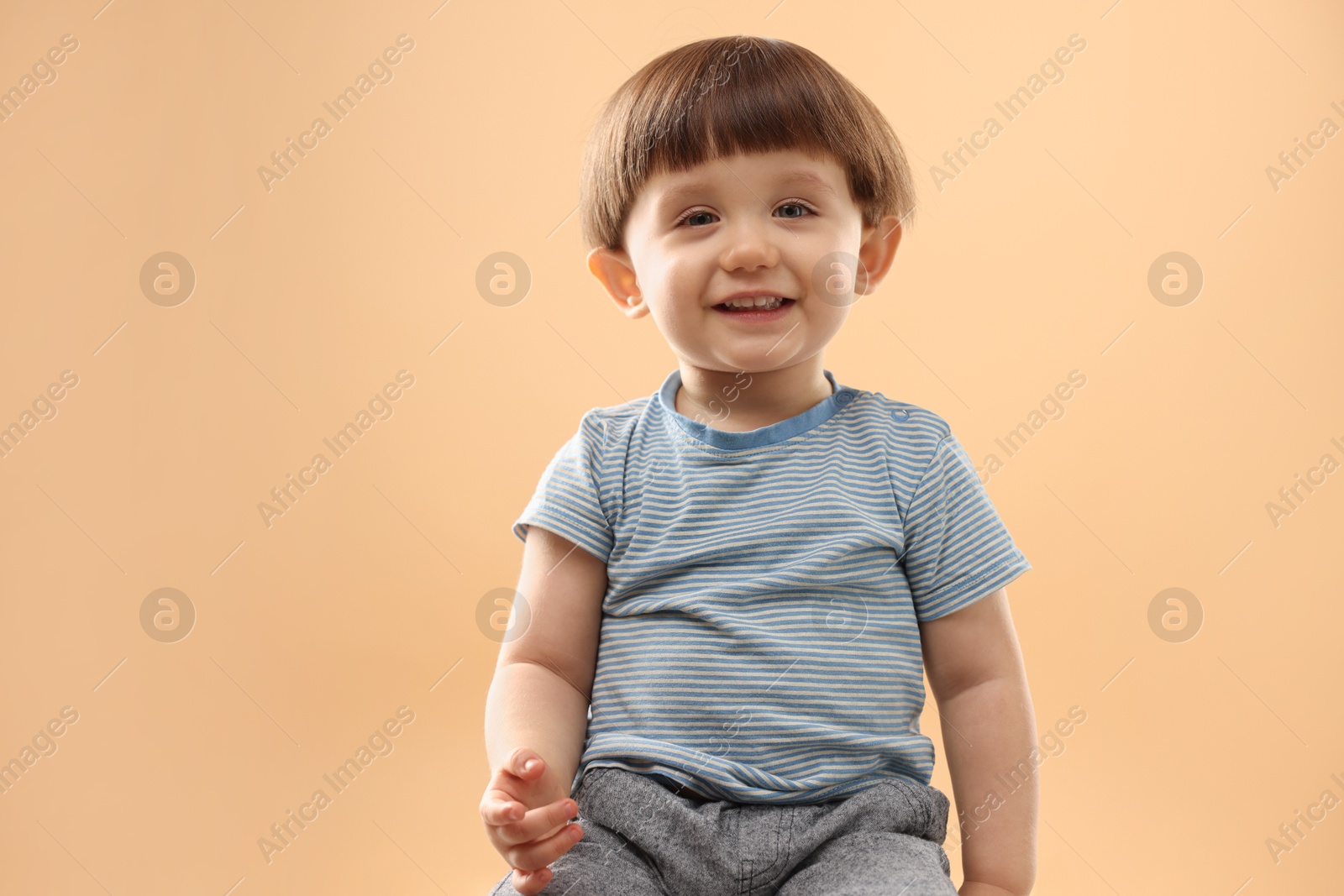 Photo of Portrait of smiling little boy on beige background. Space for text