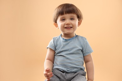 Photo of Portrait of smiling little boy on beige background. Space for text