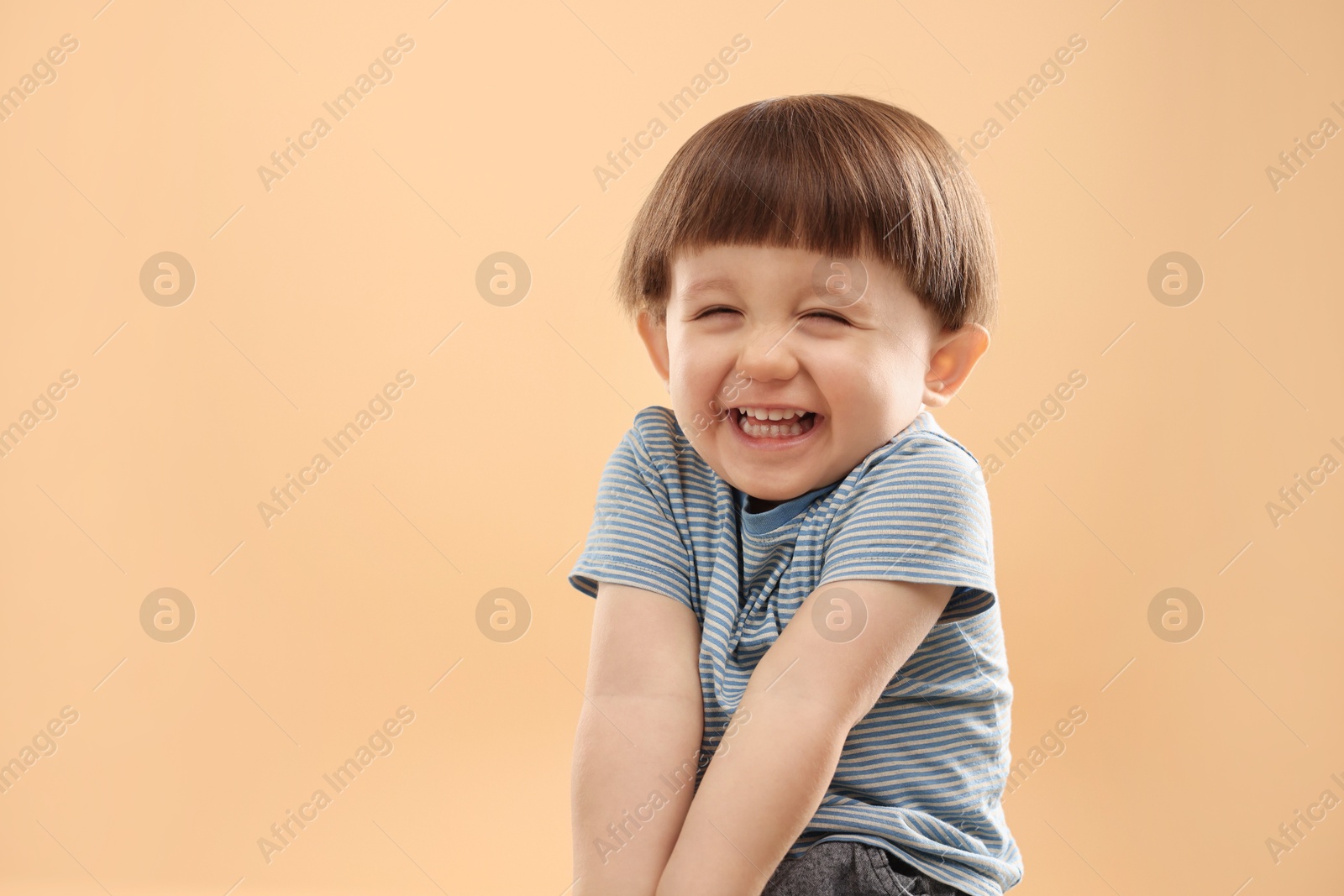 Photo of Portrait of happy little boy on beige background. Space for text