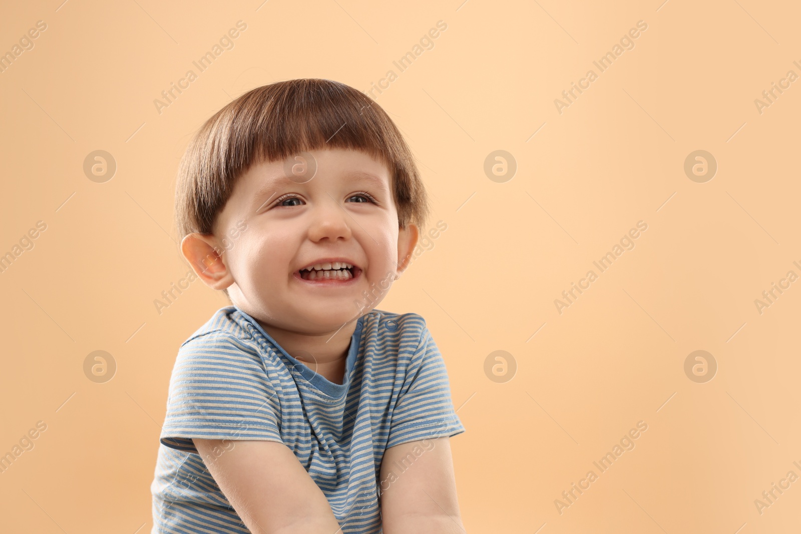 Photo of Portrait of happy little boy on beige background. Space for text