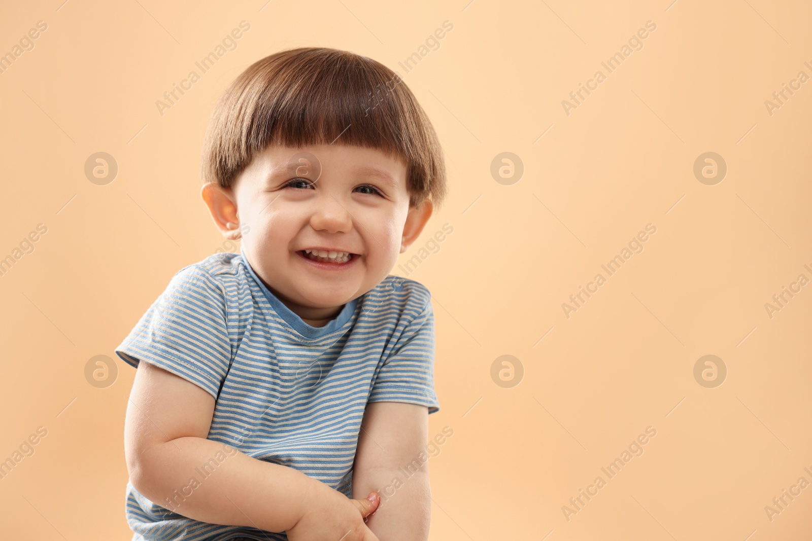 Photo of Portrait of happy little boy on beige background. Space for text