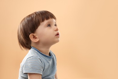 Photo of Portrait of cute little boy on beige background. Space for text