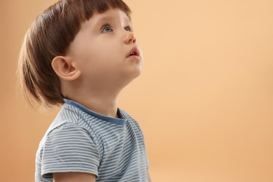 Photo of Portrait of cute little boy on beige background. Space for text