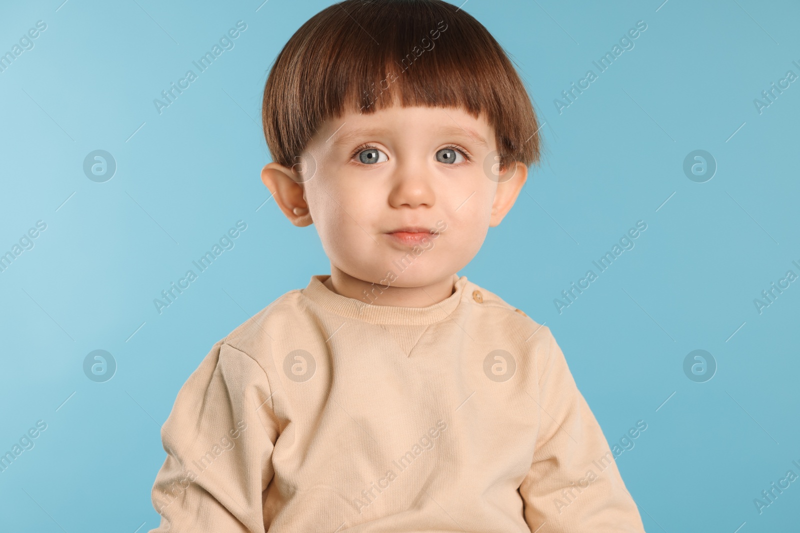 Photo of Portrait of cute little boy on light blue background