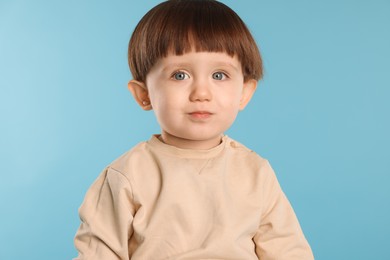 Photo of Portrait of cute little boy on light blue background