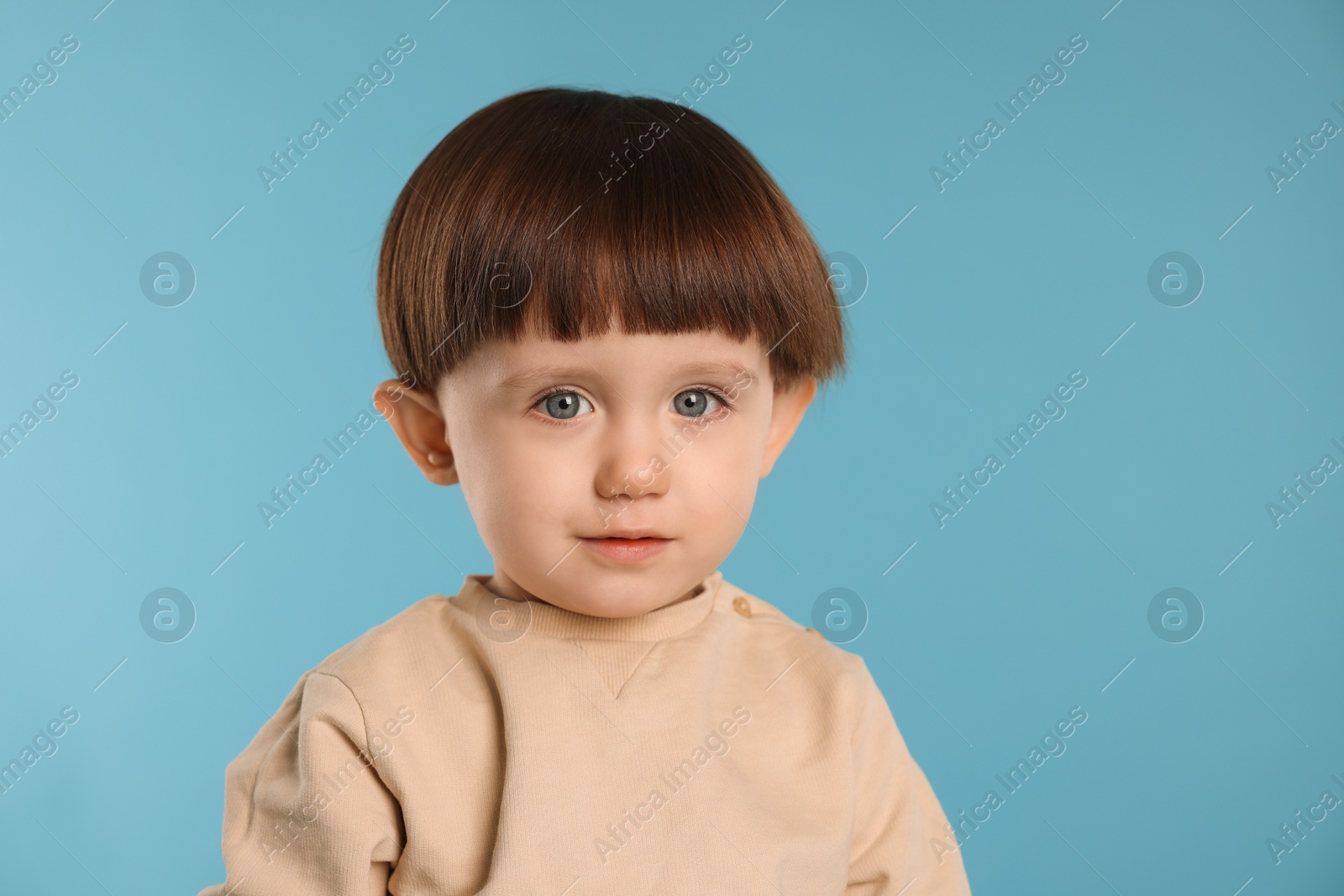 Photo of Portrait of cute little boy on light blue background