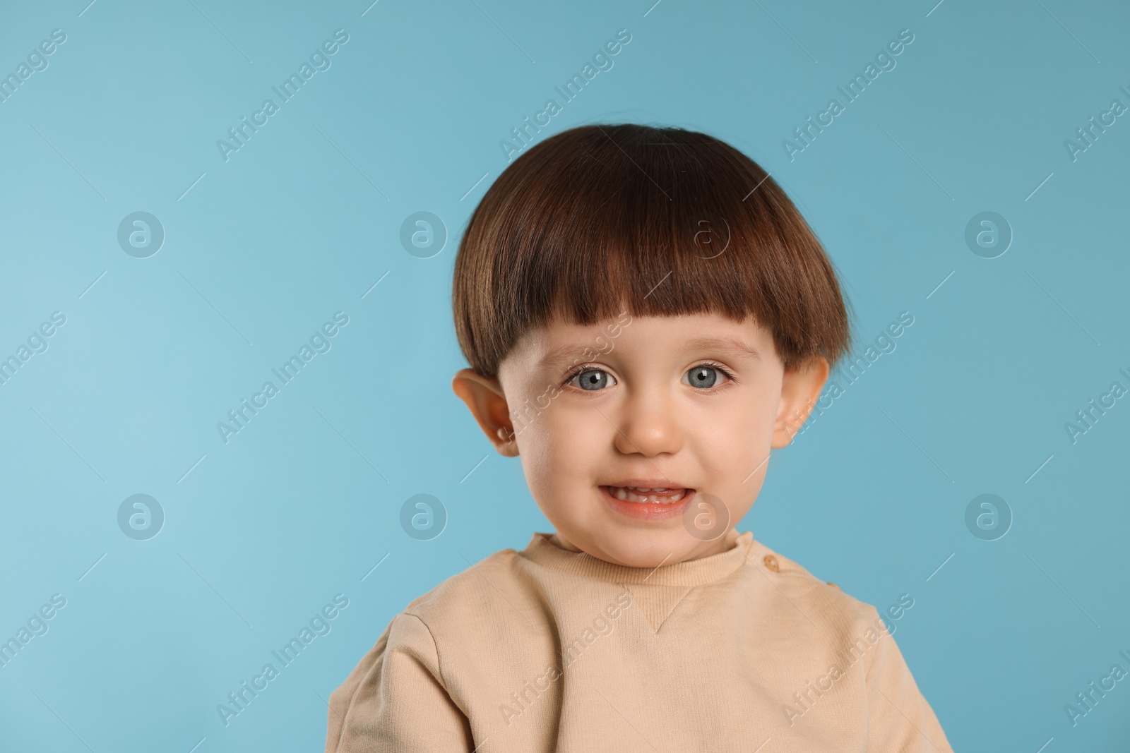 Photo of Portrait of happy little boy on light blue background. Space for text