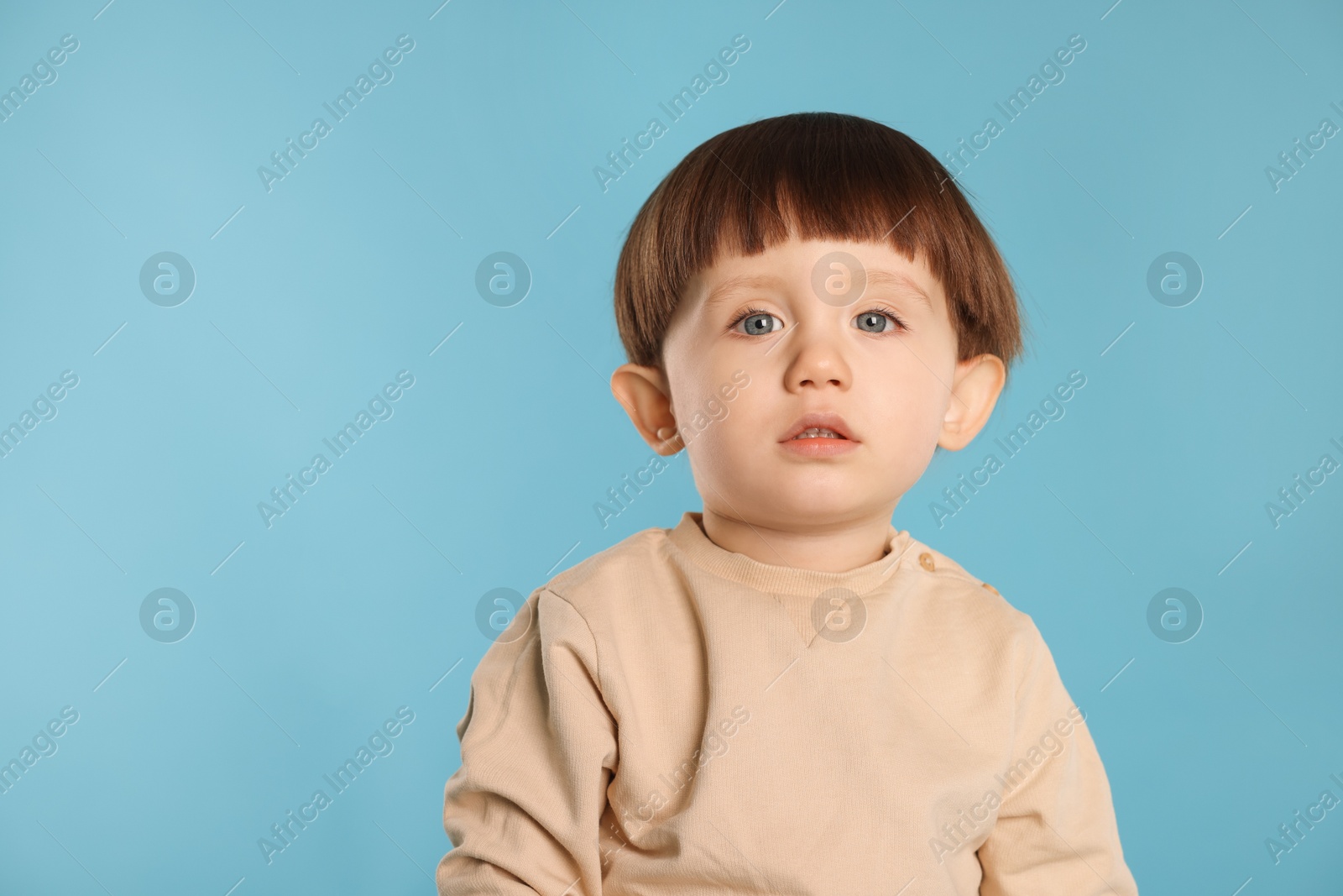 Photo of Portrait of cute little boy on light blue background. Space for text