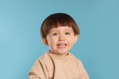 Photo of Portrait of happy little boy on light blue background