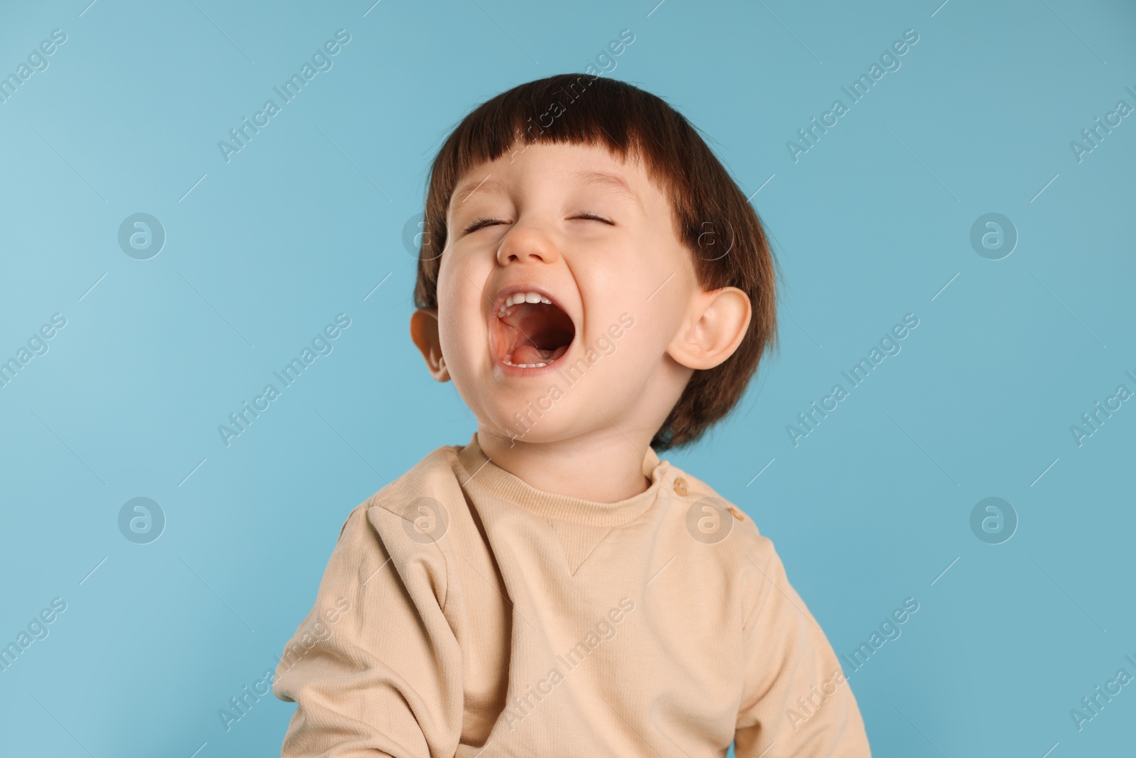 Photo of Portrait of emotional little boy on light blue background