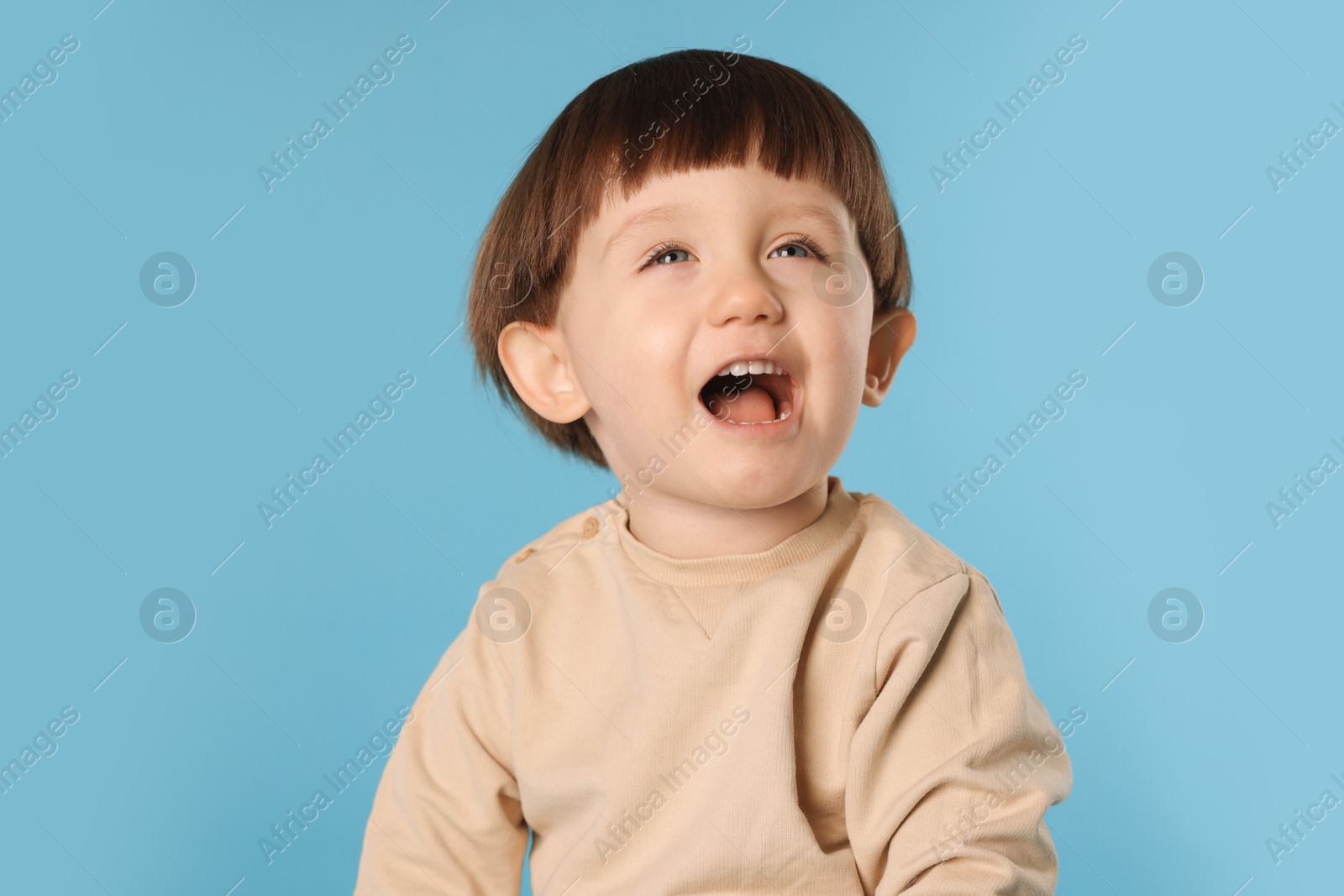 Photo of Portrait of emotional little boy on light blue background