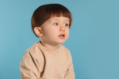 Photo of Portrait of cute little boy on light blue background. Space for text