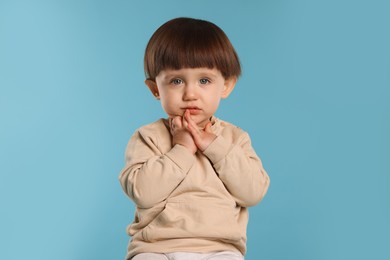 Photo of Portrait of cute little boy on light blue background