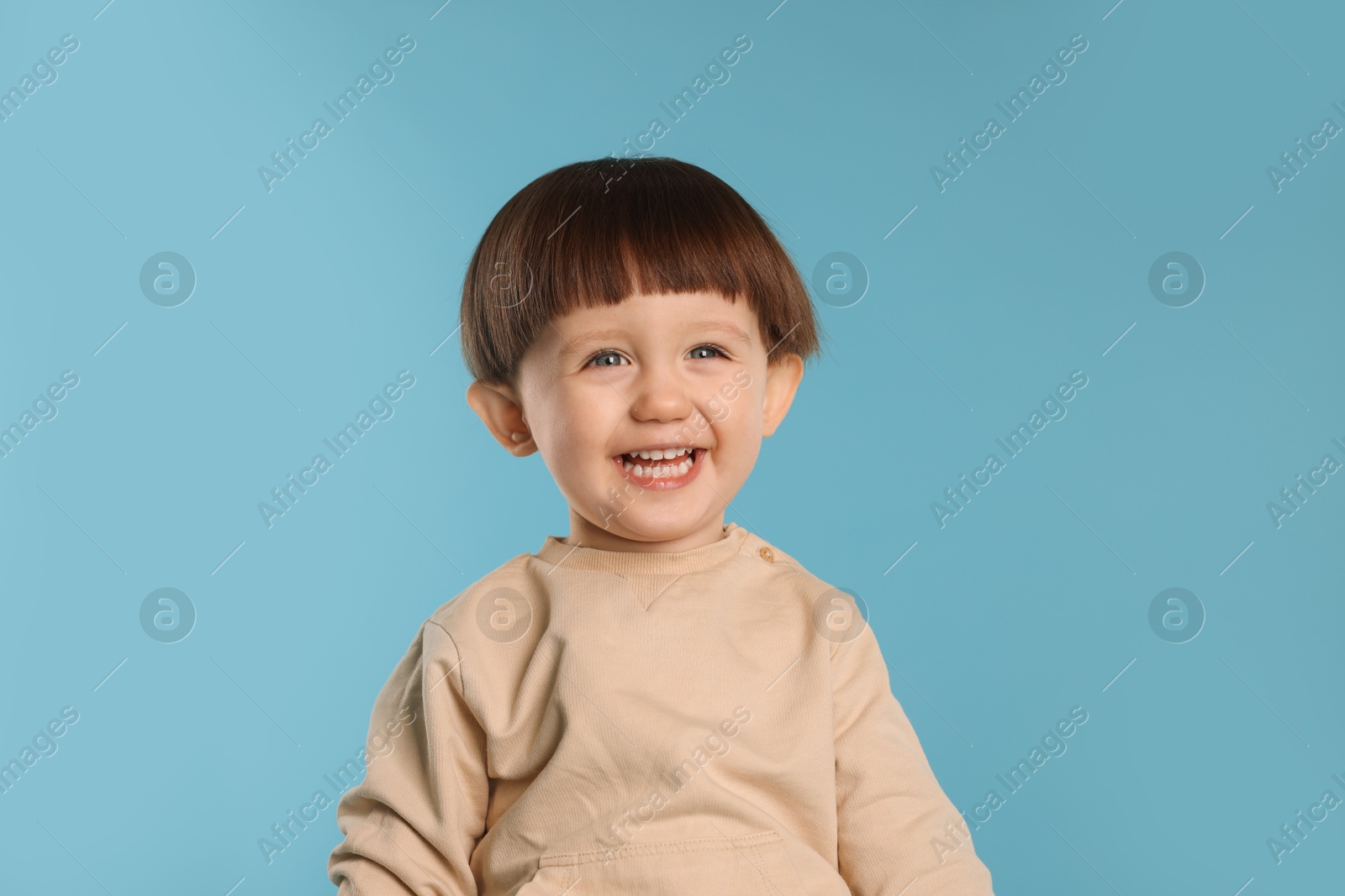 Photo of Portrait of happy little boy on light blue background