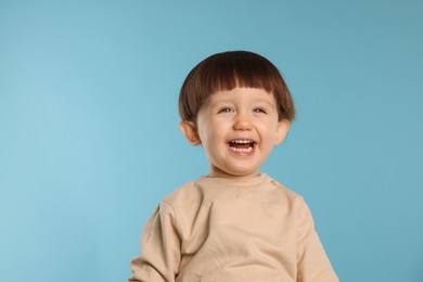 Photo of Portrait of happy little boy on light blue background. Space for text