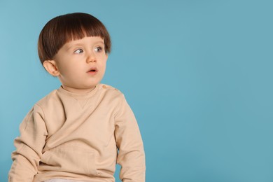 Photo of Portrait of cute little boy on light blue background. Space for text