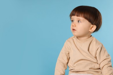 Photo of Portrait of cute little boy on light blue background. Space for text