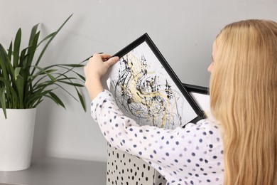 Female decorator with box of pictures indoors