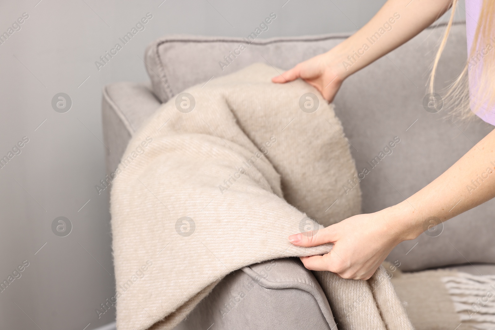 Photo of Female decorator arranging blanket onto armchair indoors, closeup