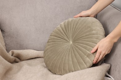 Photo of Female decorator arranging pillow onto armchair indoors, closeup