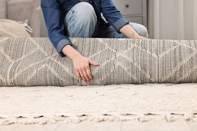 Photo of Female decorator rolling out carpet indoors, closeup