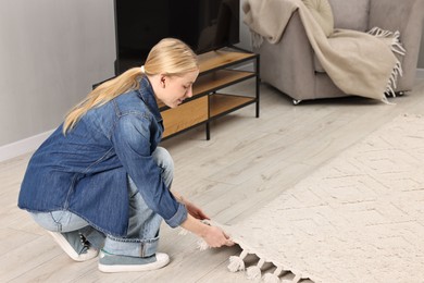 Photo of Smiling decorator placing beautiful carpet in room