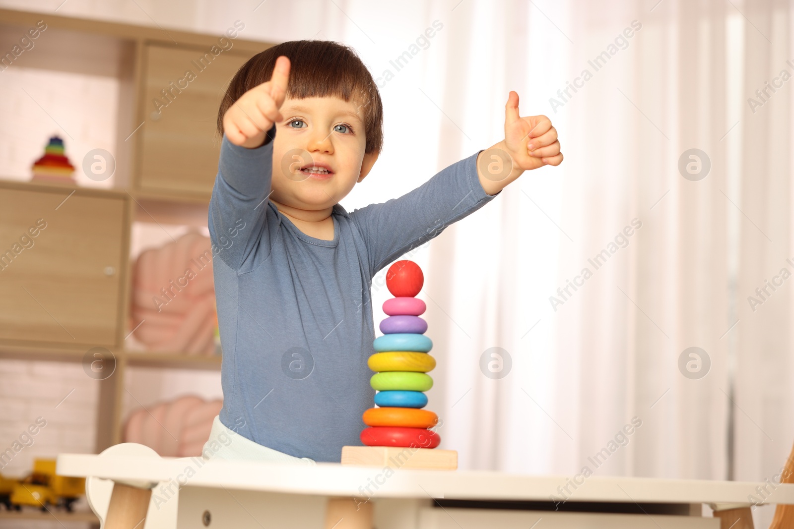 Photo of Cute little boy showing thumbs up at home