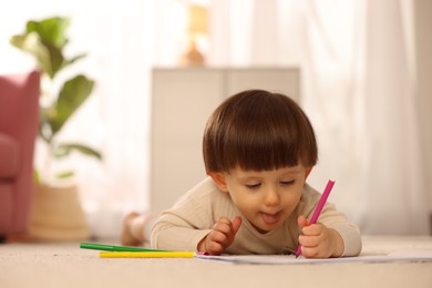 Photo of Cute little boy drawing on floor at home, space for text