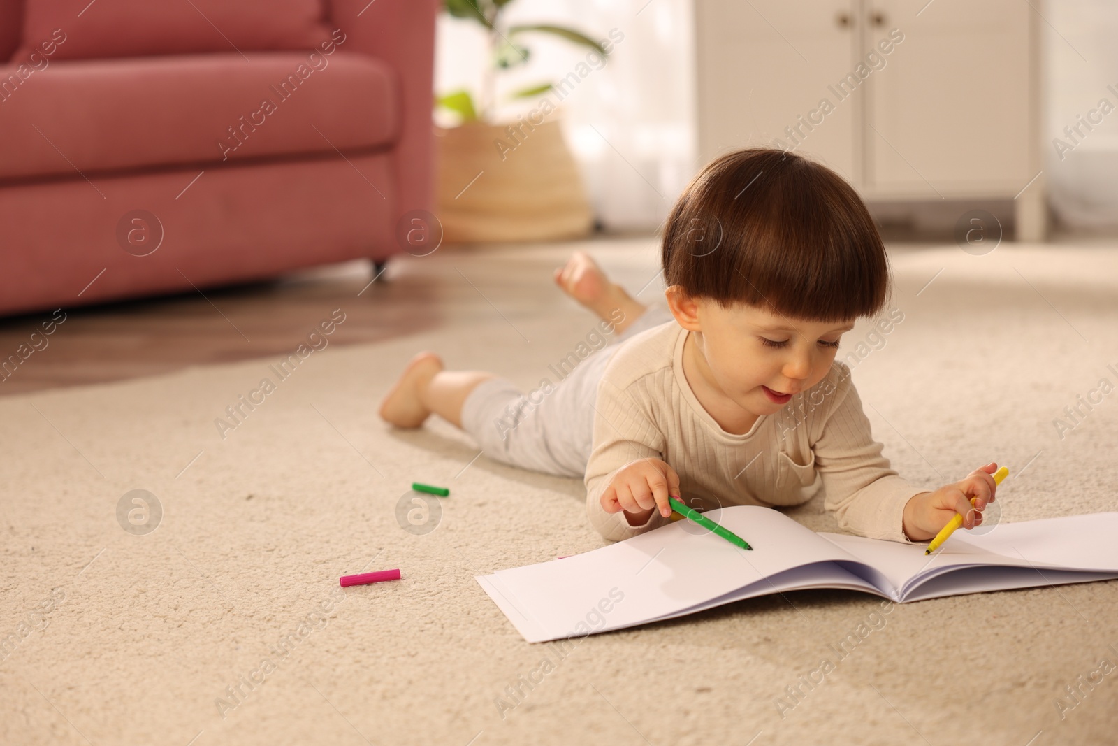 Photo of Cute little boy drawing on floor at home, space for text