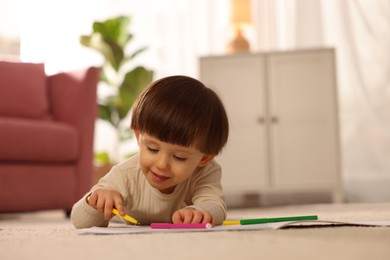 Photo of Cute little boy drawing on floor at home, space for text