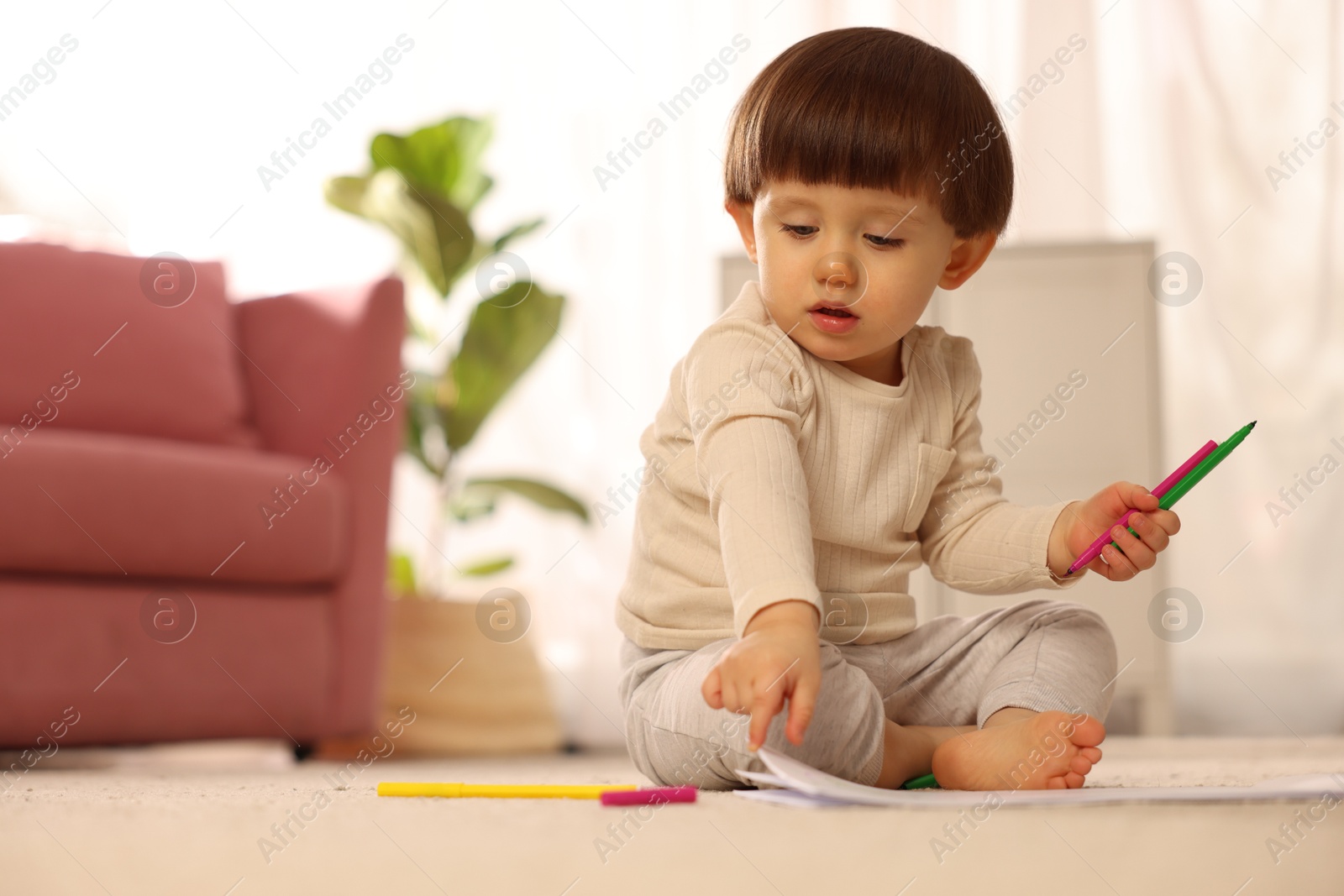 Photo of Cute little boy with felt pens on floor at home, space for text