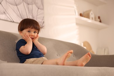 Photo of Cute little boy on sofa at home