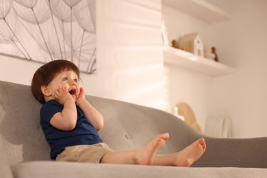 Photo of Cute little boy on sofa at home