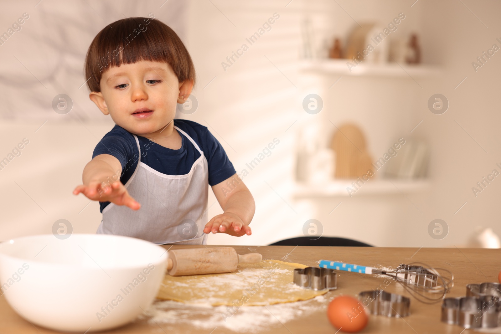 Photo of Cute little boy making dough at table indoors, space for text