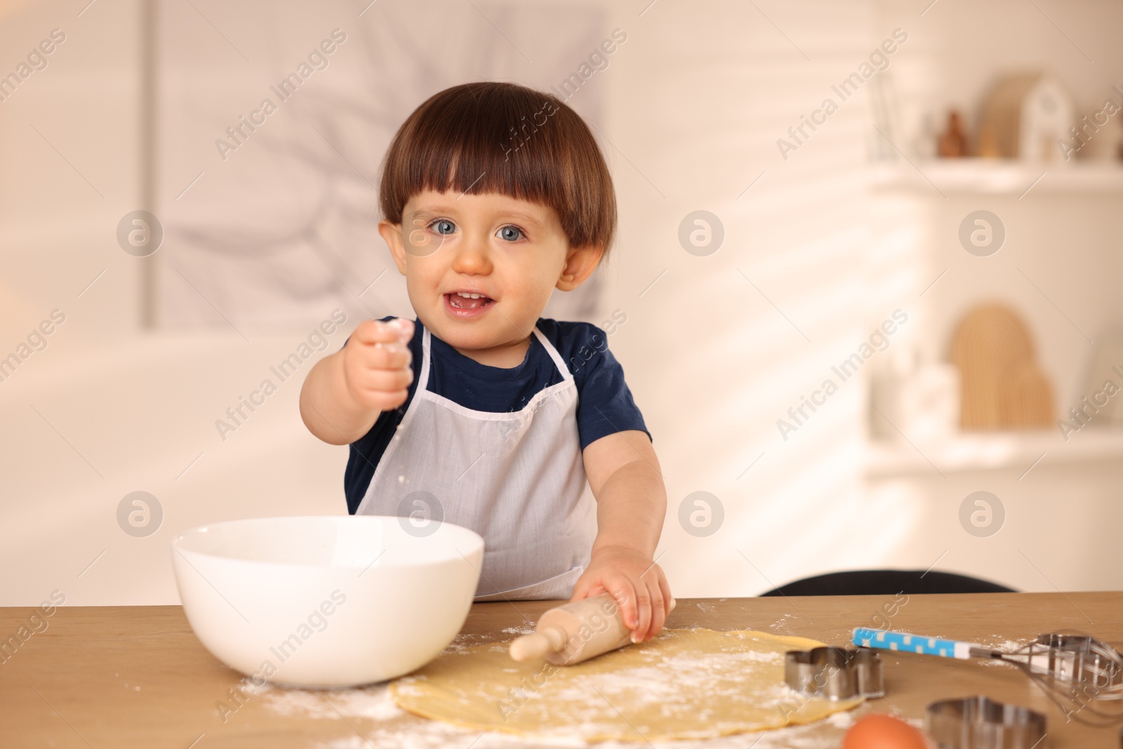 Photo of Cute little boy with rolling pin at table indoors