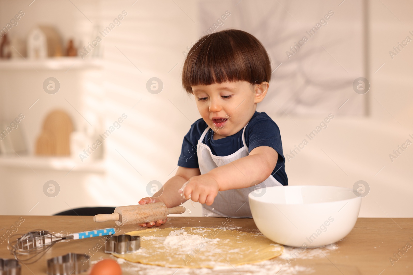 Photo of Cute little boy with rolling pin at table indoors