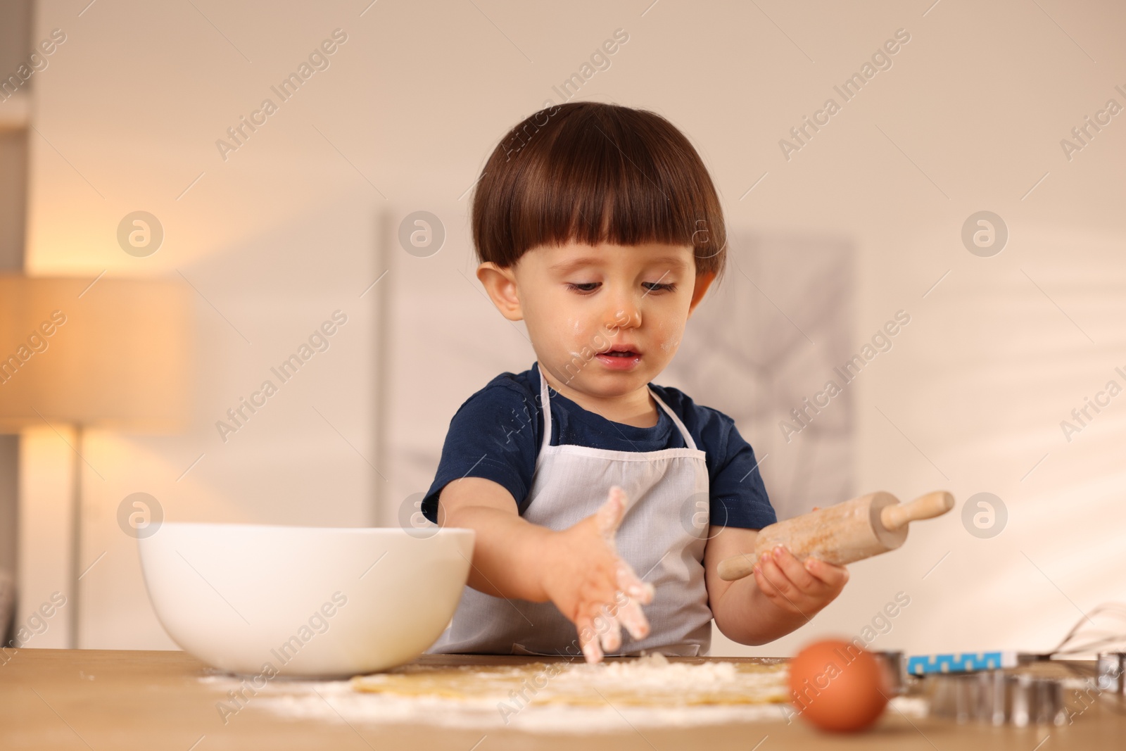 Photo of Cute little boy shaping dough with rolling pin at table indoors