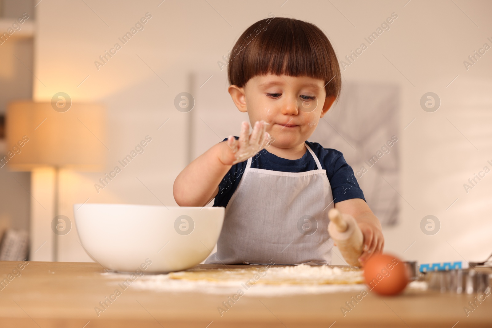 Photo of Cute little boy with rolling pin at table indoors