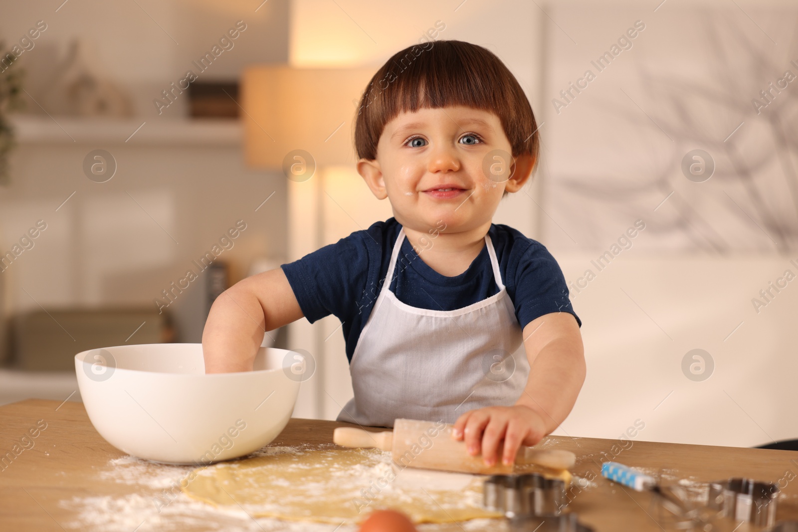 Photo of Cute little boy making dough at table indoors