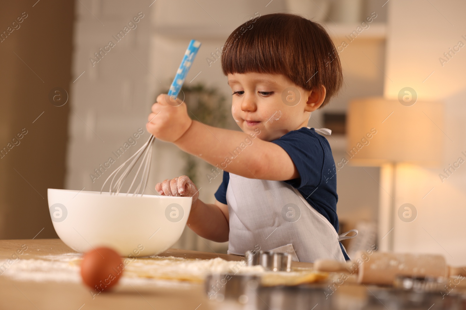 Photo of Cute little boy making dough at table indoors