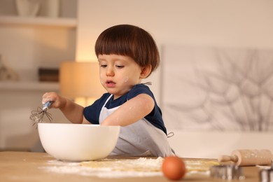 Photo of Cute little boy making dough at table indoors, space for text