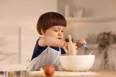 Photo of Cute little boy making dough at table indoors