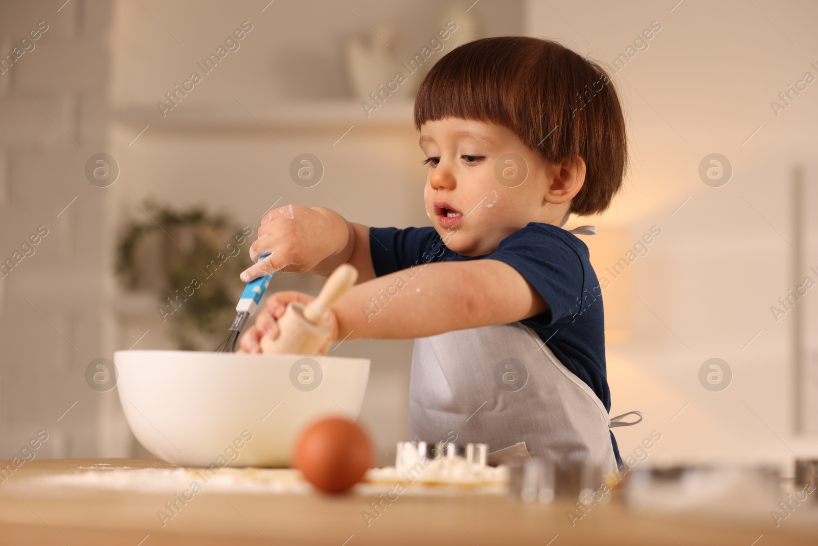 Photo of Cute little boy making dough at table indoors