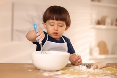 Photo of Cute little boy making dough at table indoors