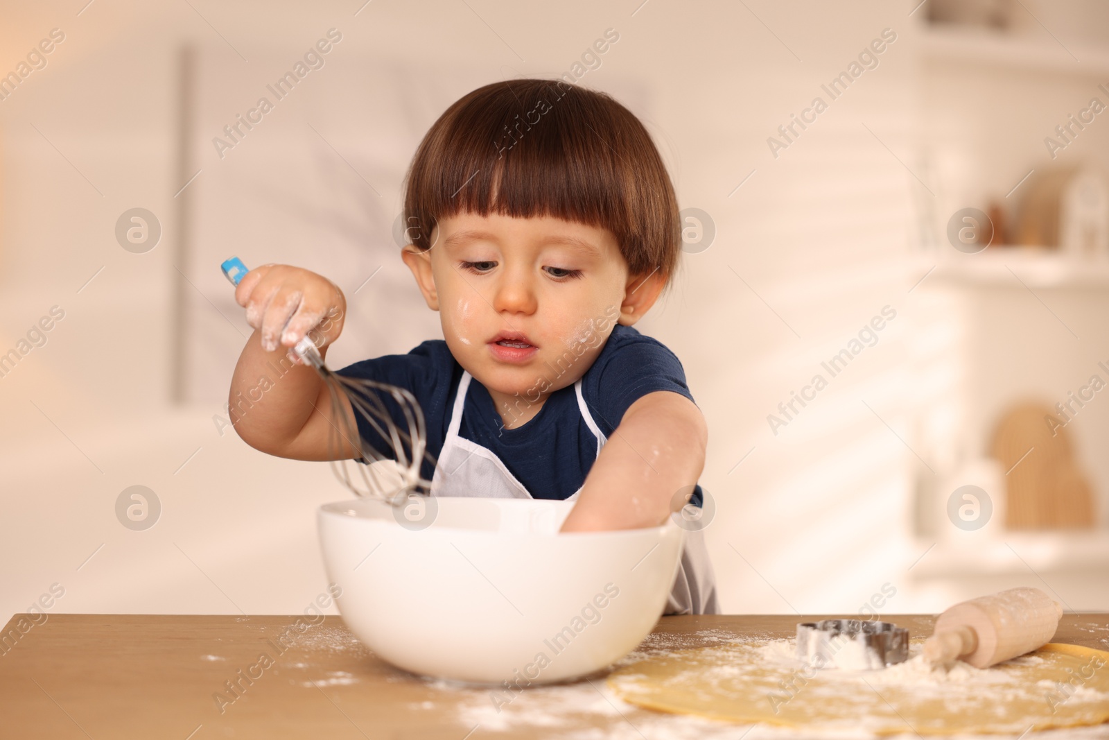 Photo of Cute little boy making dough at table indoors