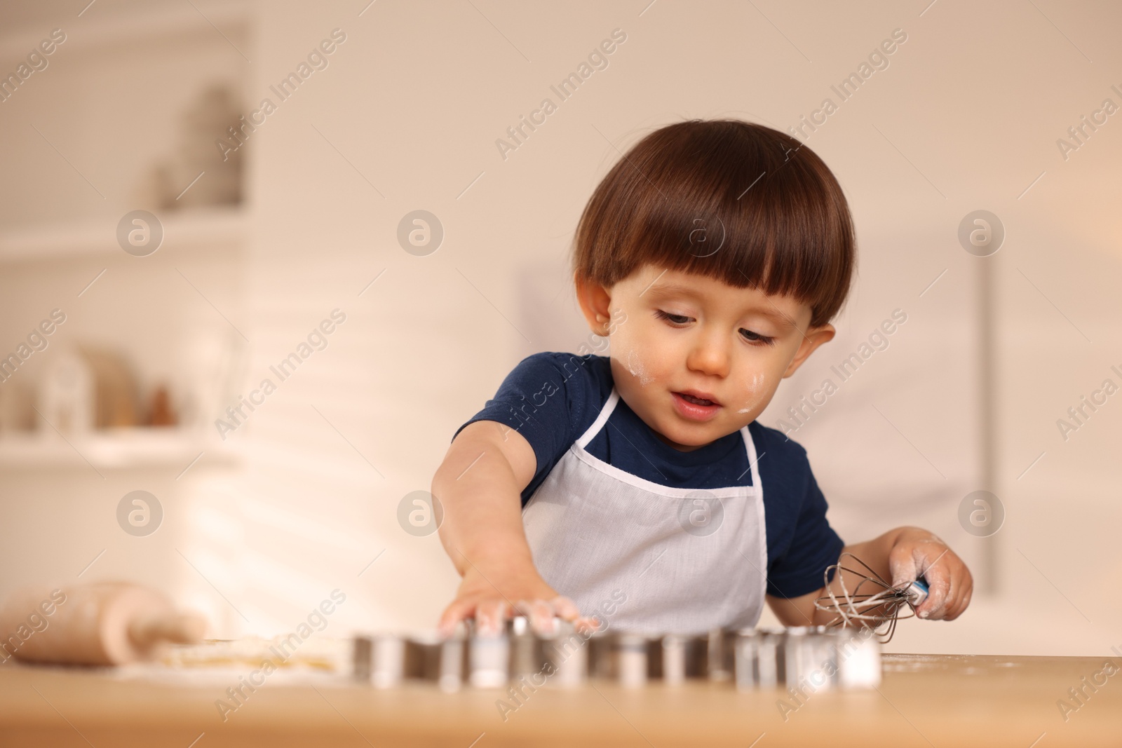 Photo of Cute little boy with whisk at table indoors, space for text