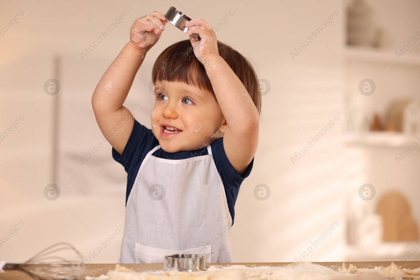 Photo of Cute little with cookie cutter at table indoors, space for text