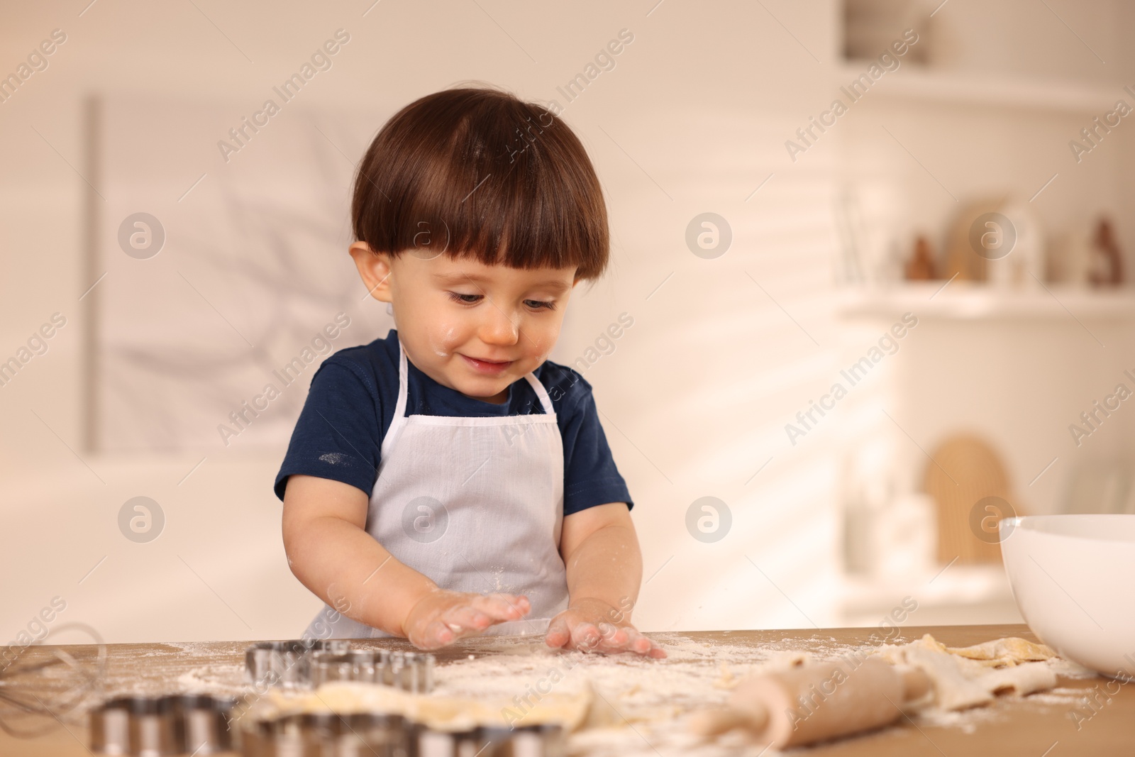 Photo of Cute little boy making dough at table indoors