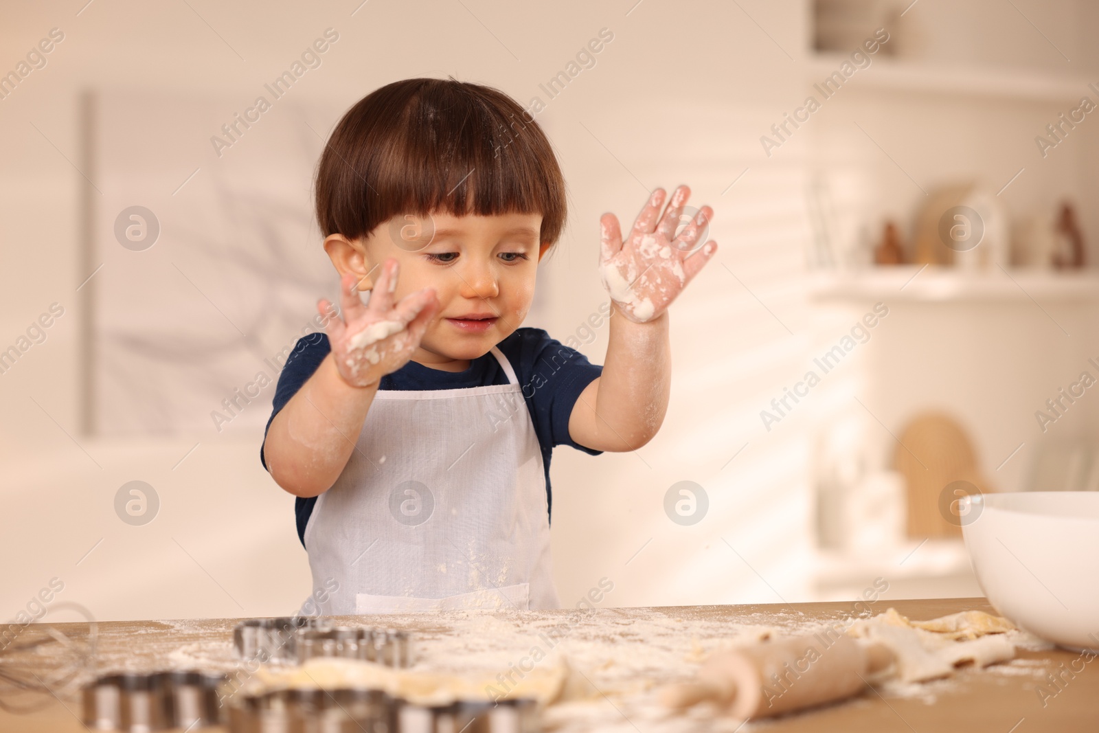 Photo of Cute little boy making dough at table indoors