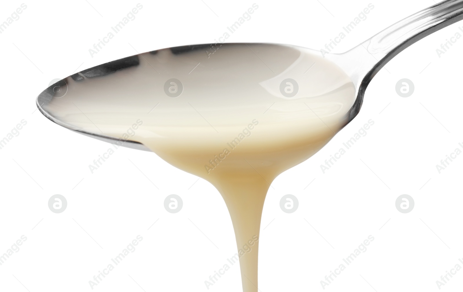 Photo of Delicious condensed milk pouring from spoon isolated on white